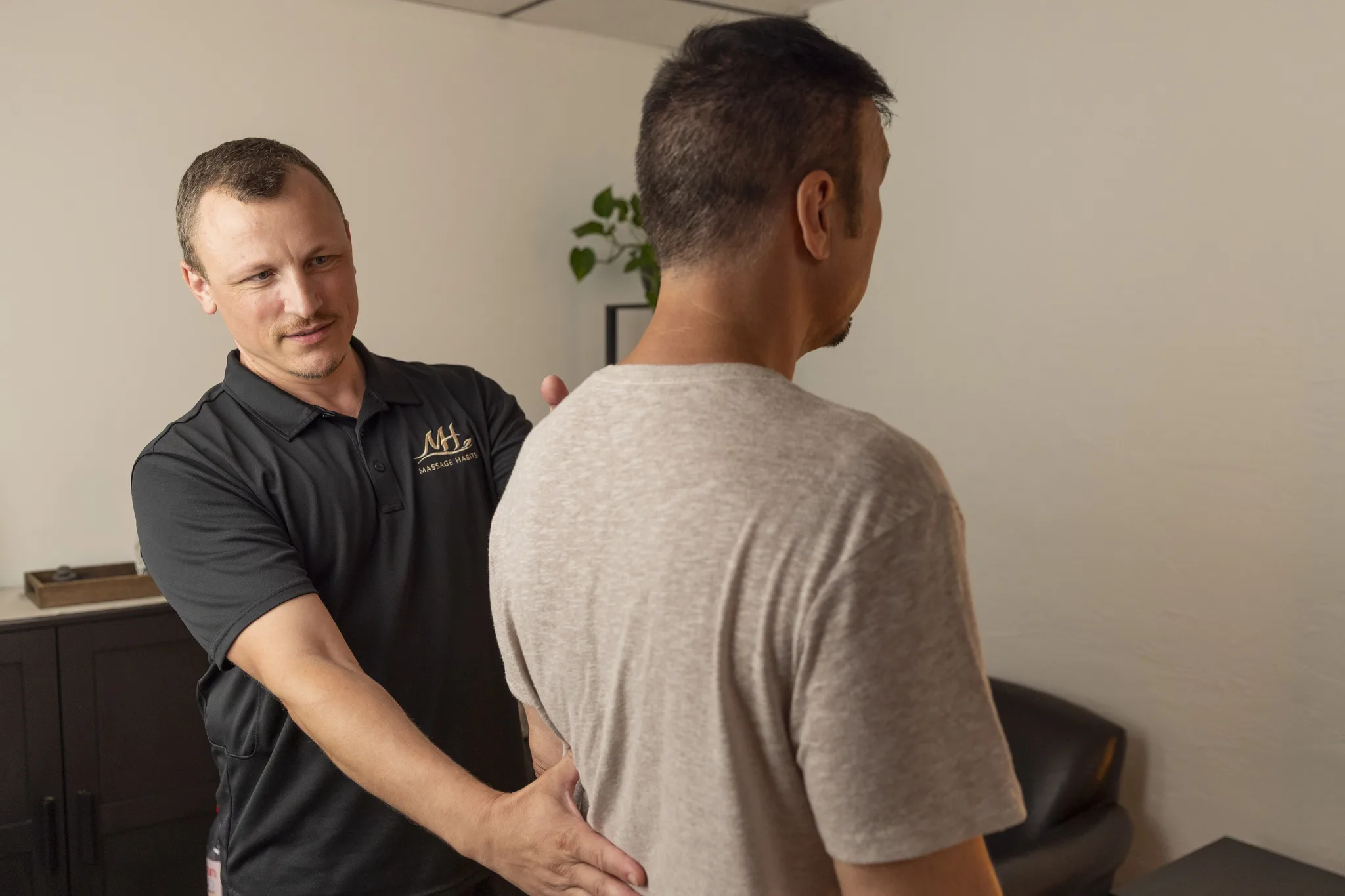Dorian talking with a client before a session, one hand on the client's upper back.